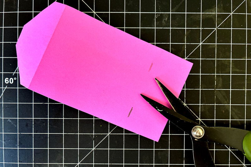 A pair of scissors cuts excess paper off of the zine holder.