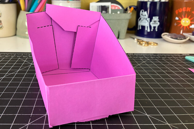 Folding the zine holder together and tucking the paper tabs into the slots.